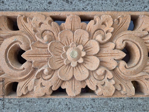 Ornamental carved brick with floral pattern, traditional architectural detail with textured stone surface
