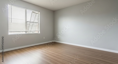 Empty unfurnished studio apartment interior with freshly painted light gray walls and wooden flooring, ready for staging or occupancy