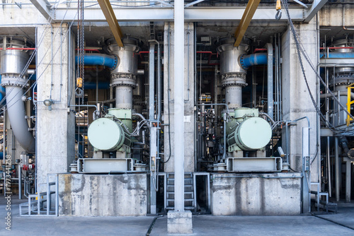 Foto Two large industrial electric motors and high-pressure pumps installed on reinforced concrete bases within a factory or power plant