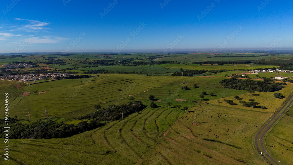 Naklejka premium Aerial view of a serene landscape with green fields and a clear blue sky