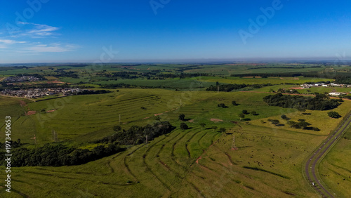 Aerial view of a serene landscape with green fields and a clear blue sky