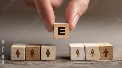 Hand placing wooden block with the letter E, forming the word employee