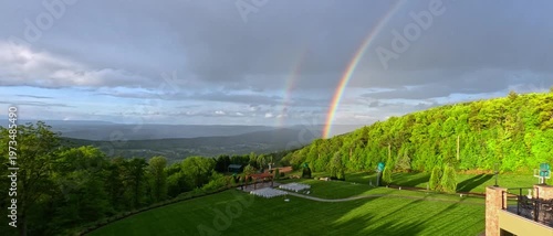 A large rainbow over a green forest on a rainy day, Pennsylvania.