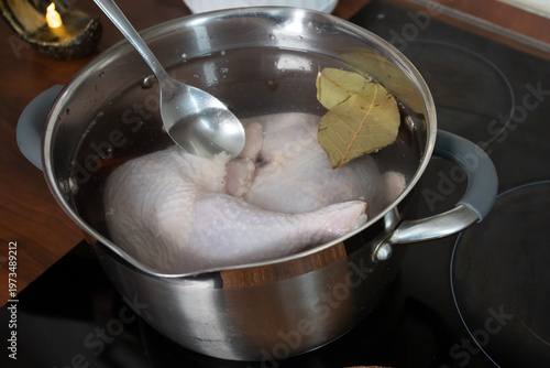 Photography close view of a pot with chicken in water and bay leaves on the stovetop capture