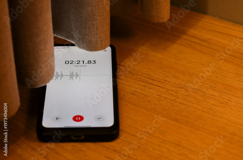 Картината върху платно Voice detection and recording app in mobile phone listening to conversation placed on the floor near window curtains