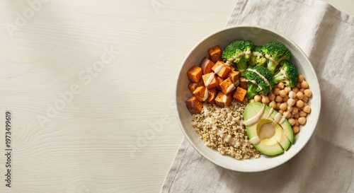 Healthy vegan buddha bowl with quinoa, avocado, sweet potato, broccoli, and chickpeas on light background