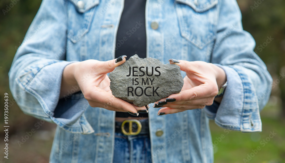 Obraz premium Female hand showing Jesus Is My Rock message on rock.