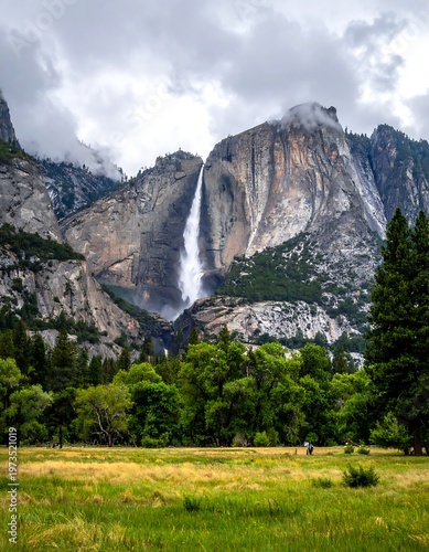 A scenic vista showcases a towering waterfall cascading from a dramatic mountain range, surrounded by lush trees and a vibrant green meadow