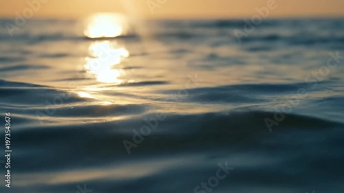 Golden sunlight reflecting on calm ocean water surface at sunset