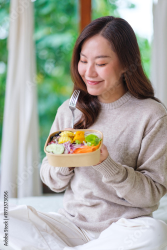 Vertical portrait image of a woman eating vegetables salad at home, Vegan, Clean food, dieting concept
