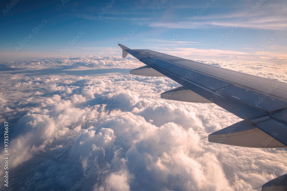 Obraz premium Airplane Wing Above Clouds During Sunset Flight.