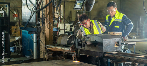Two Male Engineers Operating CNC Machine with Sparks Flying Engineers Teamwork in Controlling Automated Cutting Machine Mentor and Technician Learning CNC Operation in a Dusty Environment.