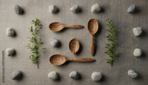 Minimalist kitchen still life with wooden utensils, stone tiles, olive branches, and textured linen fabric creating a serene, organic composition of natural materials and neutral tones