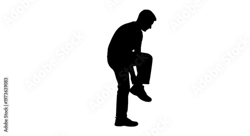 Silhouette of a man standing on one leg adjusting his shoe.
