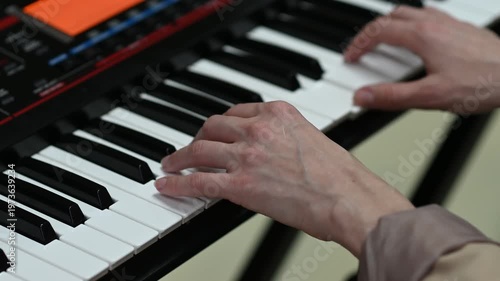 female pianist hands on black and white synthesizer keyboard, close-up view, young woman playing piano, professional musician