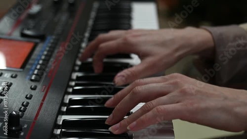 female pianist hands on black and white synthesizer keyboard, close-up view, young woman playing piano, professional musician