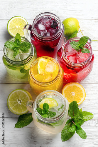 Assorted Refreshing Summer Fruit Lemonades and Cocktails in Mason Jars on White Wood