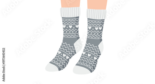 Pair of gray knitted socks with white geometric patterns and heart shapes worn on feet over a white background for winter comfort.