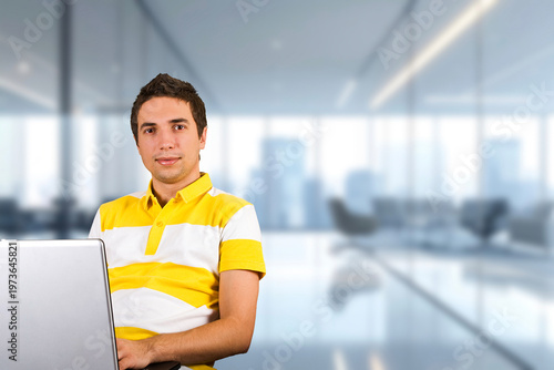 Young man smiles, holding laptop in modern office Free Download Young man smiles, holding laptop in modern office - GFXLoad