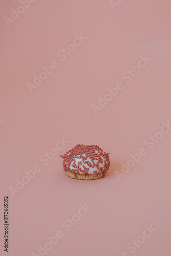 Dessert petit four with pink sprinkles on a pink background. Festive treat. Shortbread. Dessert with copy space. Sweet food for coffee. Exquisite mini cake. Fast carbohydrates. Diet violation.