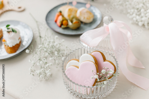 Εκτύπωση καμβά Sweet pink heart cookies in a crystal jar with a pink ribbon set on a festive table with blurred appetizers behind