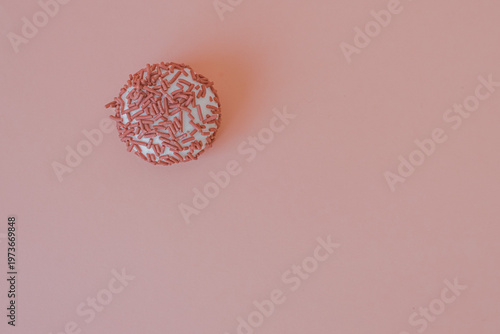 Dessert petit four with pink sprinkles on a pink background. Festive treat. Shortbread. Dessert with copy space. Sweet food for coffee. Exquisite mini cake. Fast carbohydrates. Diet violation.