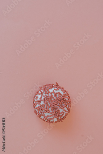 Dessert petit four with pink sprinkles on a pink background. Festive treat. Shortbread. Dessert with copy space. Sweet food for coffee. Exquisite mini cake. Fast carbohydrates. Diet violation.