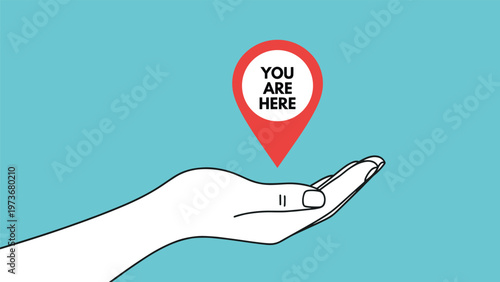 Human hand holding a red location pin with the text you are here on a light blue background for easy orientation and travel.
