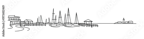 Multiple sailboats moored at docks with pier and distant lighthouse