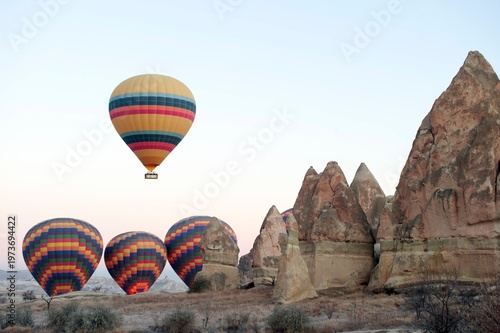Fotografie Hot air balloons flying over fairy chimneys in Cappadocia, Turkey at sunrise