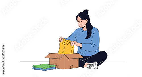 Young woman sitting on the floor and carefully folding a yellow shirt, to pack into a cardboard box for moving or donation.