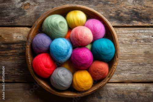 Colorful wool balls arranged in a wooden bowl on a table surface