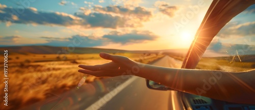 Arm out of car window enjoying sunset road trip freedom on open countryside road