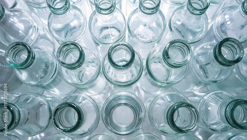 a bunch of empty glass bottles of different shapes and sizes clustered together on a plain surface