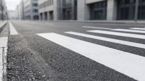 Close-up of pedestrian crosswalk with white stripes on asphalt road in urban district. Modern buildings in background, geometric perspective from ground level
