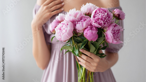 Woman holding a bouquet of pink peonies in an elegant dress