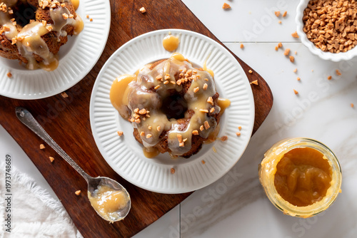 Sticky toffee pudding desserts topped with caramel sauce and toffee bits.