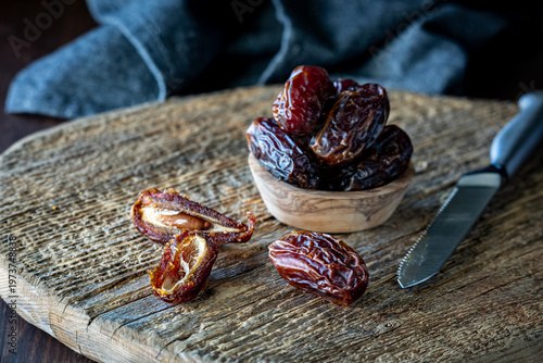 A close up of fresh raw Medjool dates on a rustic wooden board.