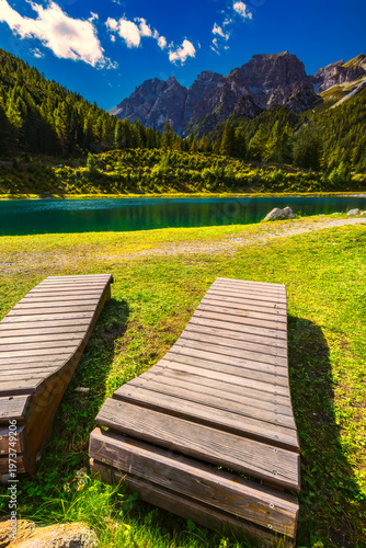 Mountain lake with wooden loungers and dramatic alpine peaks