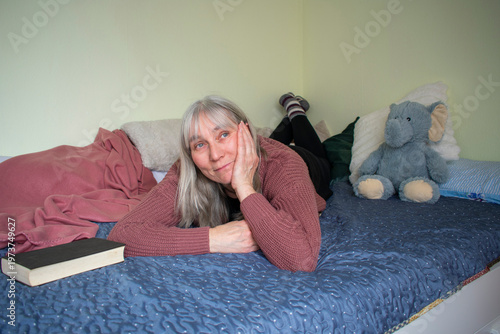 Senior woman lying on bed resting her head on hand looking relaxed