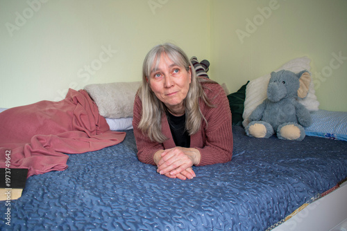 Senior woman lying on bed looking up thinking and dreaming at home