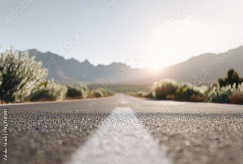Low-angle close-up of a textured asphalt road with white dividing line in sharp focus
