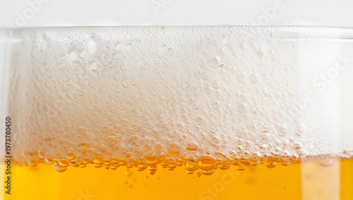 A glass of cold beer with a thick layer of froth on top, set against a plain background. The captures the refreshing and quenching qualities of the drink.