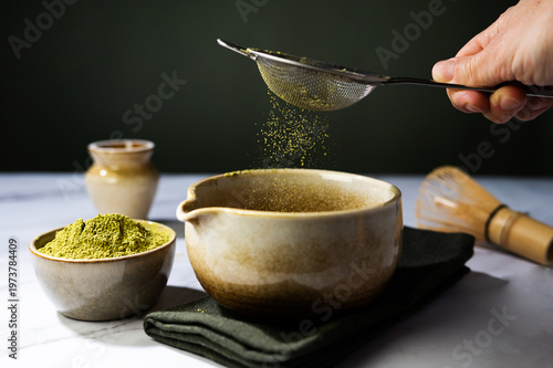 Close-up of matcha powder being sifted through a sieve, preparing traditional Japanese green tea.
