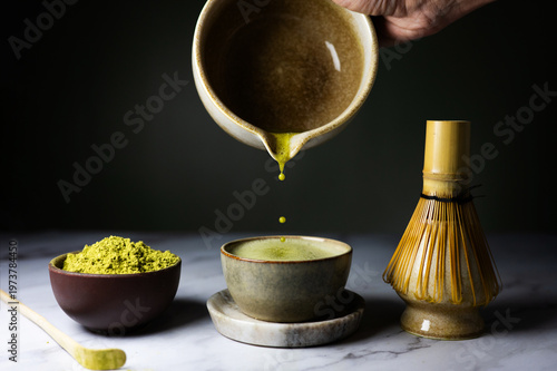 Close-up of a woman pouring freshly whisked matcha from a bowl into a cup.