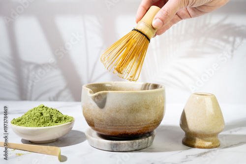 Hand whisking matcha powder into a smooth tea in a bowl with a bamboo whisk.