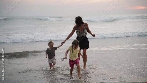 Mother and kids having fun together on the beach at sunset, enjoying quality family time by the ocean. Warm pink light, joyful atmosphere, and carefree moments of vacation, childhood, single parent