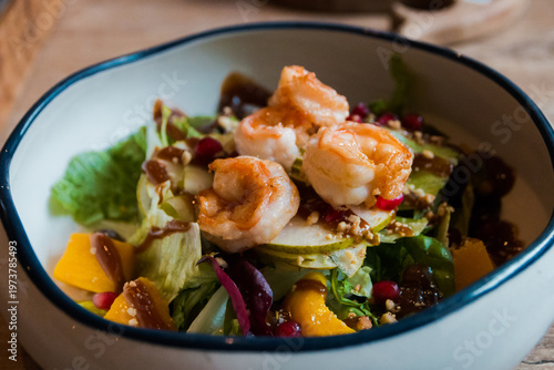 Fresh green salad leaves with shrimp, mango and sauce in a plate