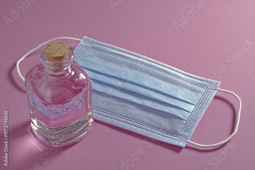 Hand Sanitizer and Surgical Face Mask on Pink Background