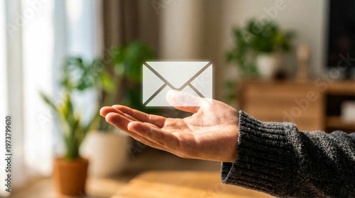 Hand holding glowing email envelope icon in bright home office setting